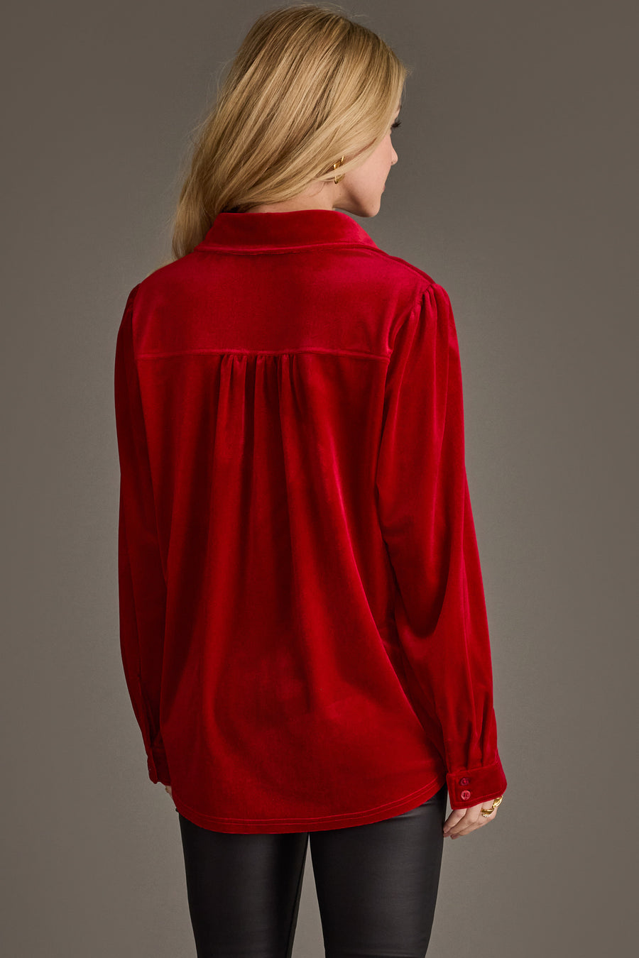 A woman with blonde hair is seen from behind wearing the Red Velvet Button Up by Panache Apparel Collection and black pants, standing against a plain gray background.