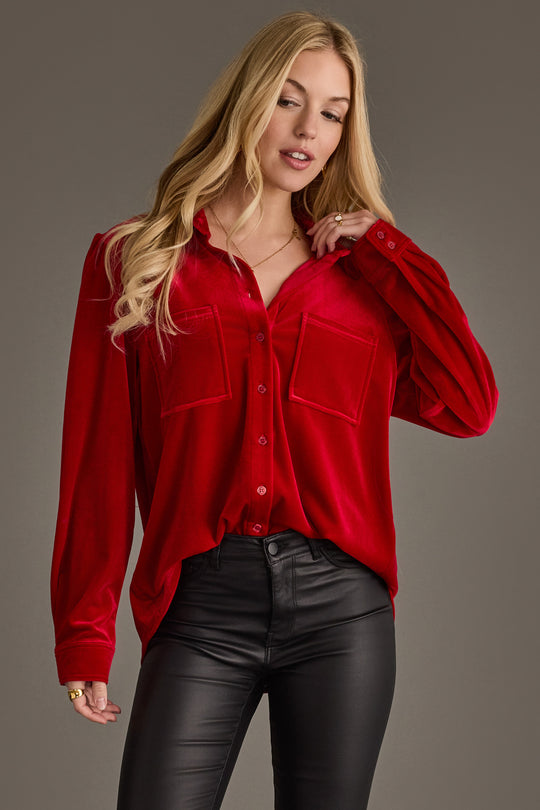 A woman wearing the Panache Apparel Collection Red Velvet Button Up and black leather pants stands against a plain gray background.