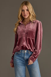 A woman with long, wavy blonde hair wears the Panache Apparel Collection Mauve Velvet Button Up with blue jeans, smiling softly in front of a plain gray background.