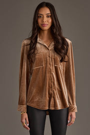 A woman models the Tan Velvet Button Up by Panache Apparel Collection—a long-sleeve, tan velvet shirt with front pockets—paired with black pants against a plain gray background.