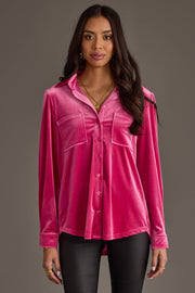 A woman in the Panache Apparel Collection Bright Pink Velvet Button Up with two front pockets and black pants stands against a gray background, looking forward with a neutral expression.