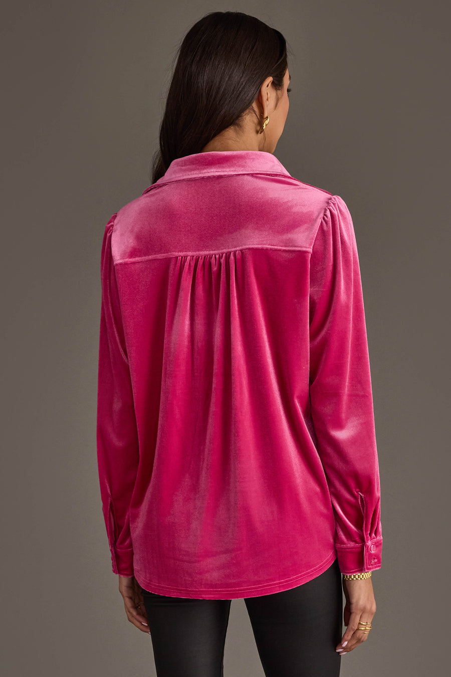 A person with long dark hair wears the Bright Pink Velvet Button Up by Panache Apparel Collection with black pants, shown from the back against a plain brown background.