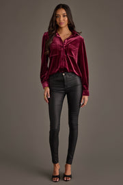 Woman with long wavy hair stands against a plain background, wearing the Panache Apparel Collection Maroon Velvet Button Up, black skinny pants, and black open-toe heels. She looks forward with a neutral expression.