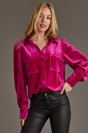 A woman models the Panache Apparel Collection Fuchsia Velvet Button Up with black leather pants, posing confidently with one hand on her hip against a plain gray background.