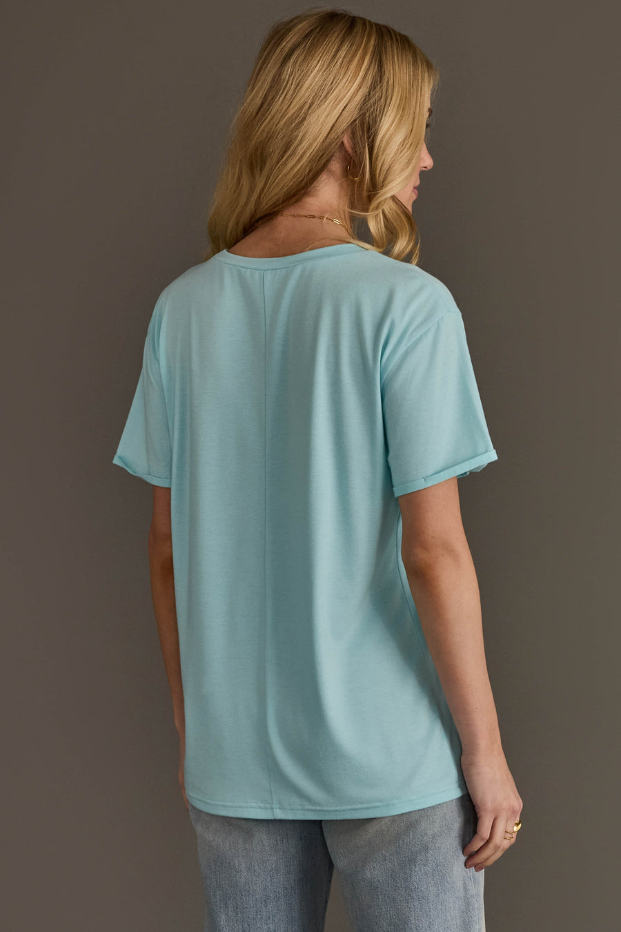 A woman viewed from behind wearing a Light Blue Christmas Trees Tee and grey jeans.