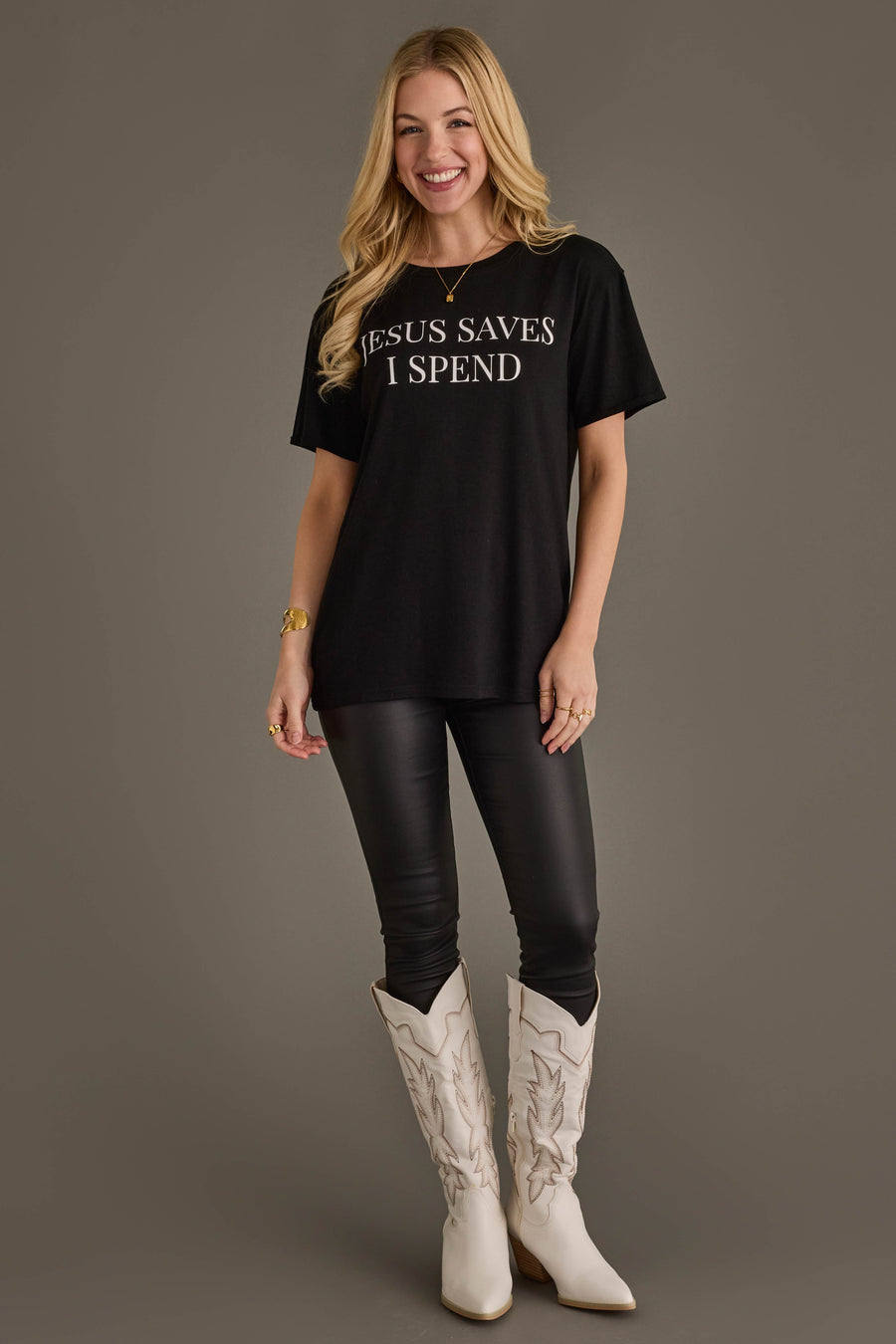 Woman wearing Panache Apparel’s black Jesus Saves I Spend graphic tee with white cowboy boots.