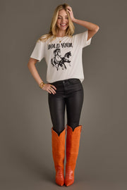 Woman wearing Panache Apparel’s white Hold Your Horses western graphic tee with orange cowboy boots.