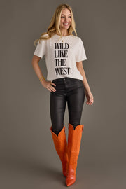 Woman wearing Panache Apparel’s white Wild Like The West western graphic tee with orange cowboy boots.