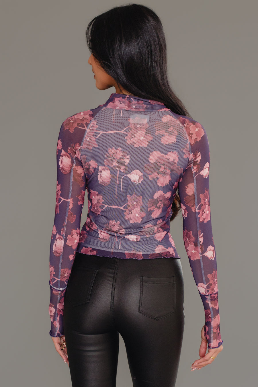 Model with long dark hair wearing the Panache Apparel Collection Reddish Brown Floral Mesh Top and black leather pants, shown from the back against a plain gray background.