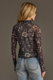 A person with long blonde hair wears the Panache Apparel Collection Gray & Cream Floral Mesh Top and light blue jeans, facing away from the camera against a neutral background.