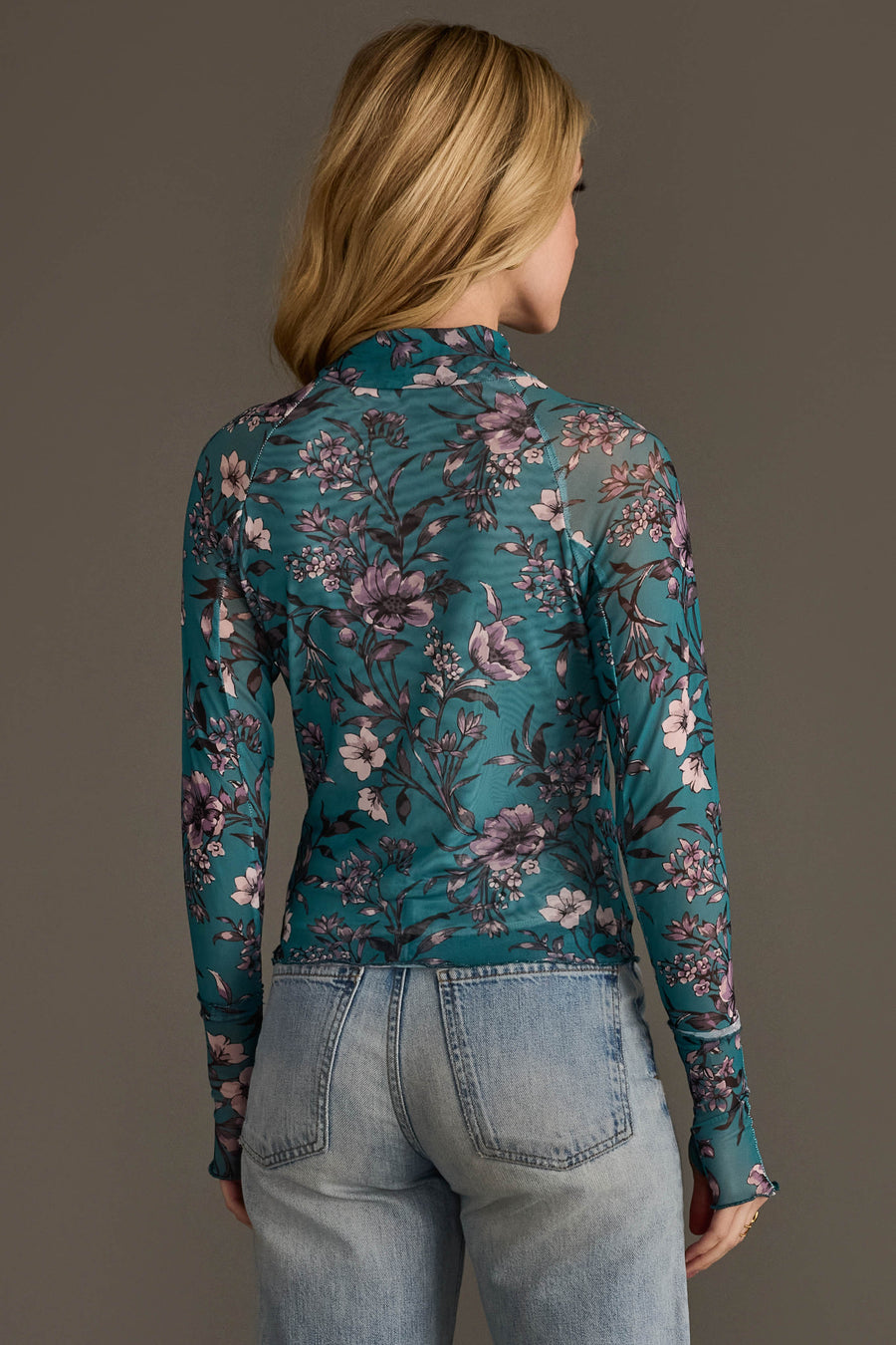 A person with long blonde hair, seen from behind against a plain background, is wearing the Panache Apparel Collection’s Teal, Cream & Light Pink Floral Mesh Top paired with light blue jeans.