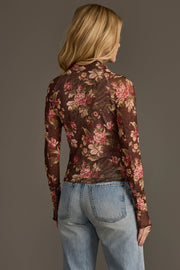 A woman with blonde hair, seen from behind, wears the Panache Apparel Collection’s Brown, Cream & Burgundy Floral Mesh Top paired with light blue high-waisted jeans against a plain background.