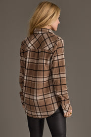 A woman with long blonde hair is facing away, wearing the Tan, White & Black Plaid Button Up from Panache Apparel Collection and black pants, standing against a plain gray background.