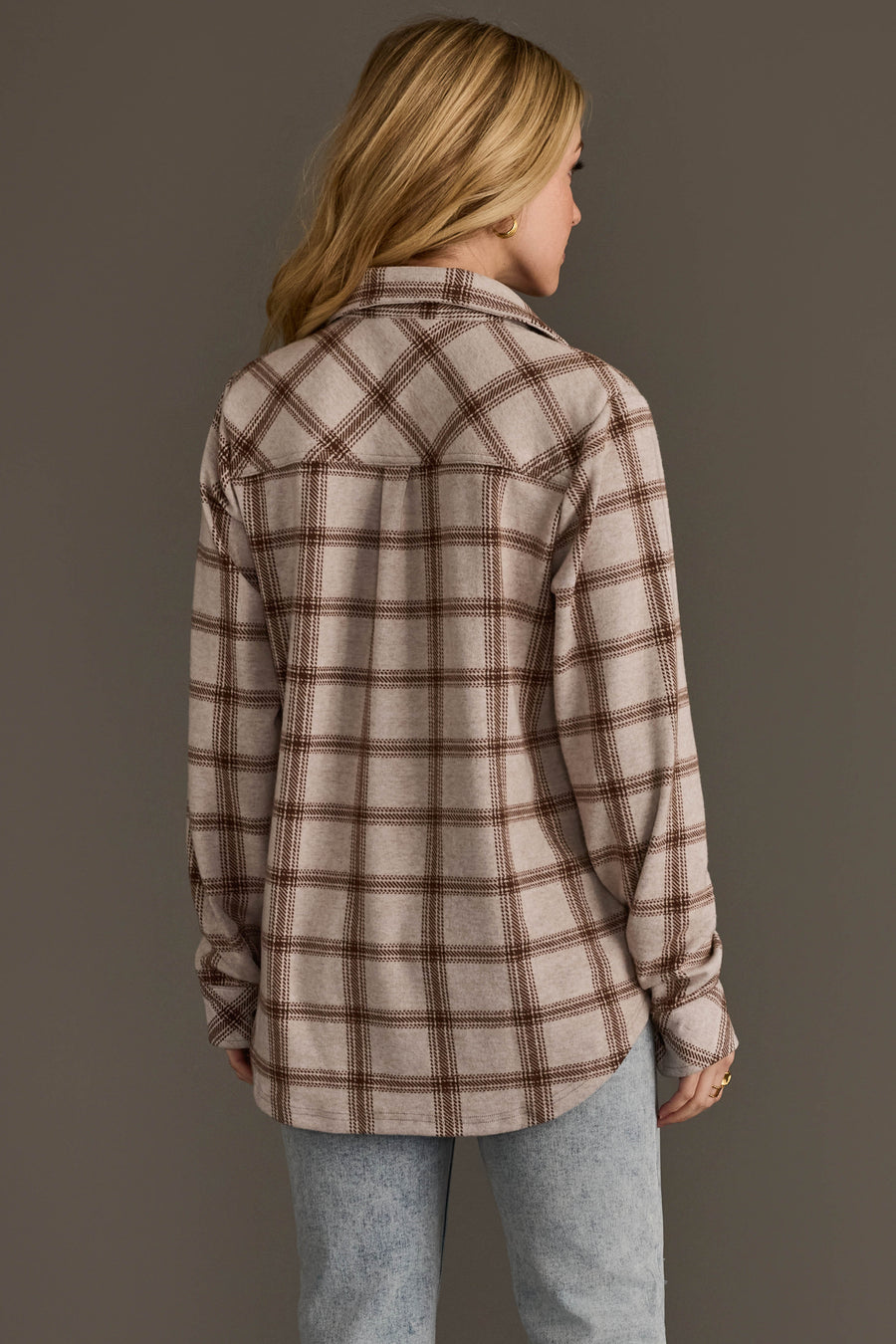 A person with long blonde hair wears the Panache Apparel Collection Light Taupe & Brown Plaid Button Up and light blue jeans, standing with their back to the camera against a plain gray background.