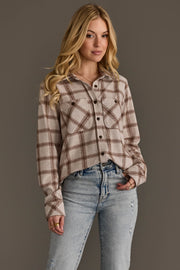 A woman with long blonde hair is wearing the Panache Apparel Collection Light Taupe & Brown Plaid Button Up and light blue ripped jeans, standing against a plain gray background.