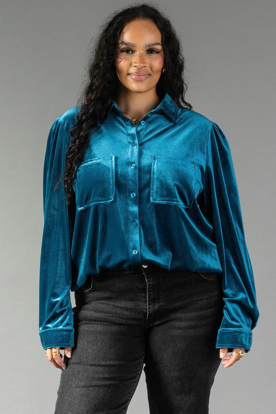 A person wearing a Dark Teal Velvet Button Up long-sleeved shirt with two chest pockets and black pants.