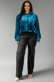 A person wearing a relaxed fit, dark teal velvet Dark Teal Velvet Button Up shirt from Panache Apparel Collection and black jeans.