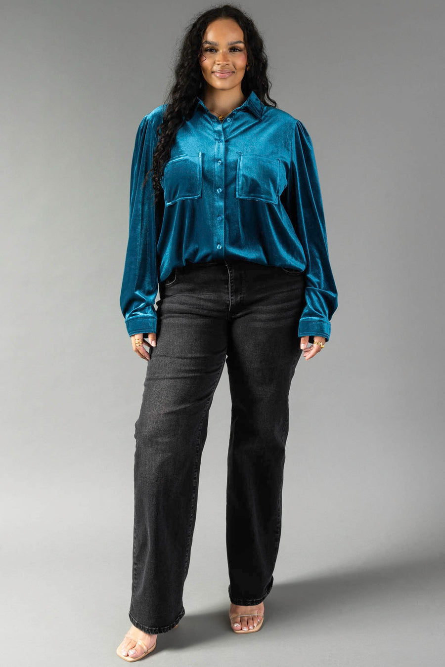 A person wearing a relaxed fit, dark teal velvet Dark Teal Velvet Button Up shirt from Panache Apparel Collection and black jeans.