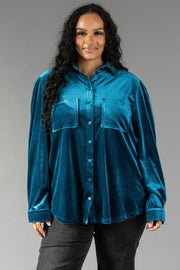 A person wearing a Dark Teal Velvet Button Up, a long-sleeved, relaxed-fit shirt in dark teal velvet with two chest pockets.