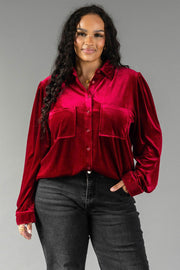 A woman wears a relaxed fit, burgundy velvet Burgundy Velvet Button Up with two front chest pockets and dark jeans.