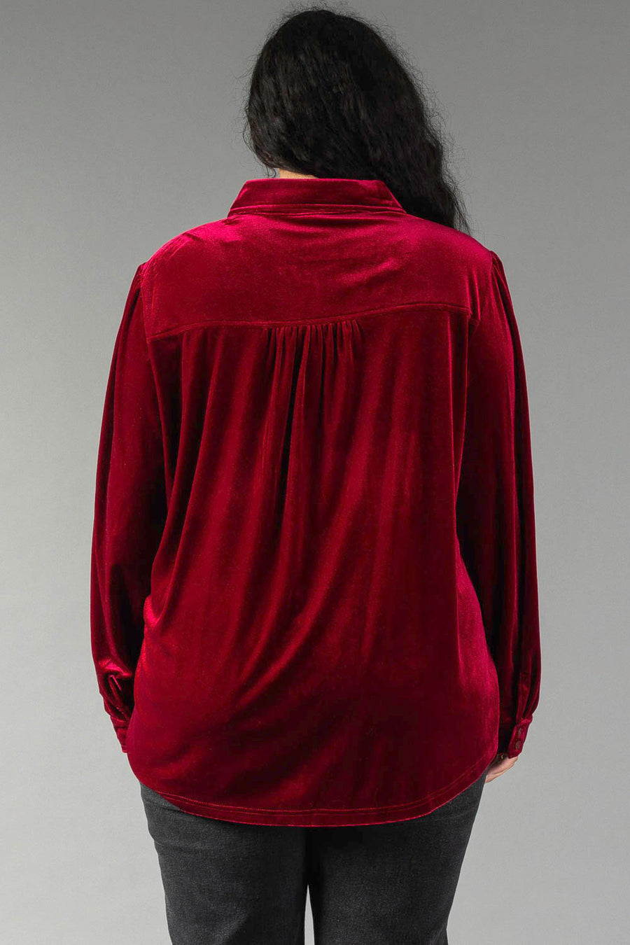 Back view of a person wearing a Burgundy Velvet Button Up, featuring long sleeves, a collared neckline, and a pleated back yoke.