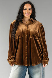 A smiling woman wears a long-sleeved Bronze Velvet Button Up in bronze with front pockets and light-wash jeans.