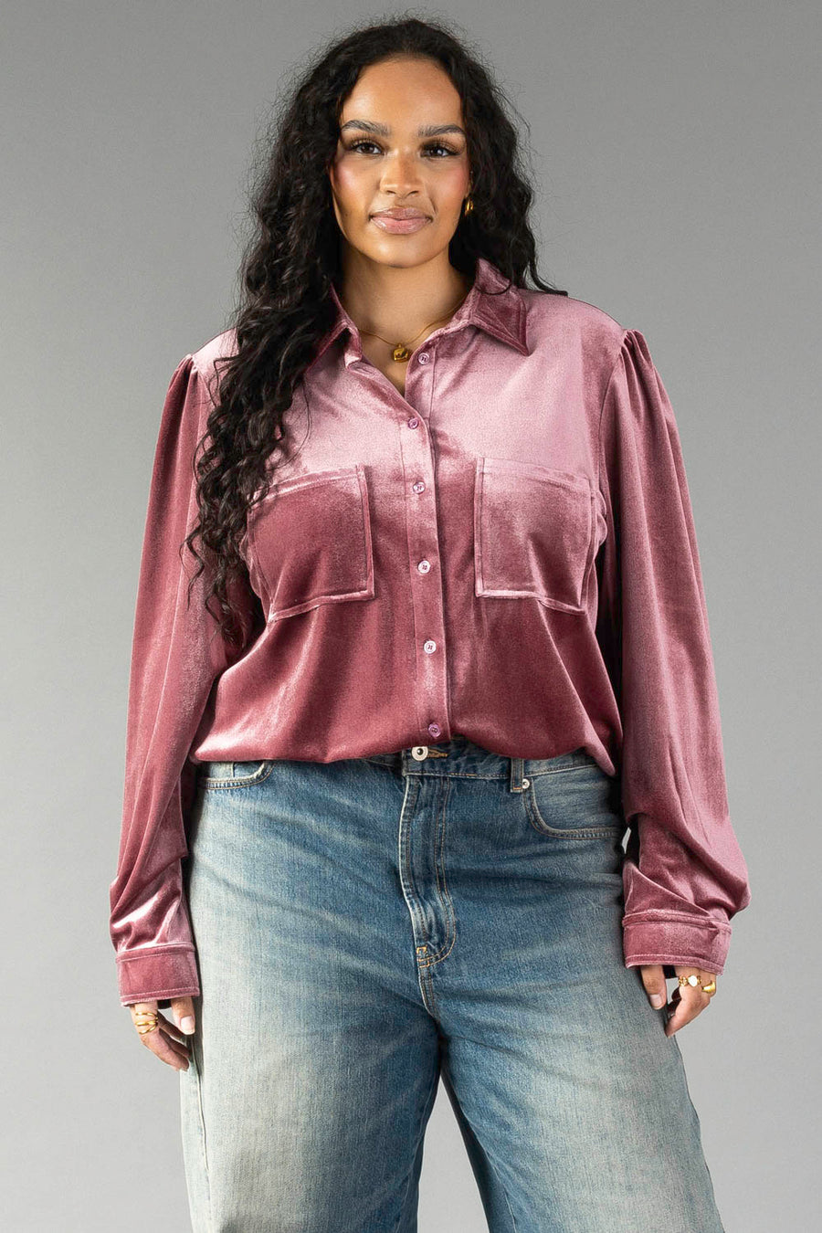 A person wearing a mauve velvet button-up shirt from the Panache Apparel Collection with chest pockets and blue jeans.
