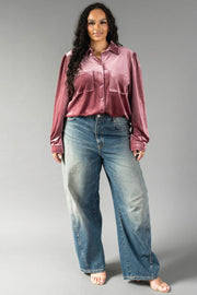 A woman wearing a Mauve Velvet Button Up shirt and wide-leg blue jeans from Panache Apparel Collection.