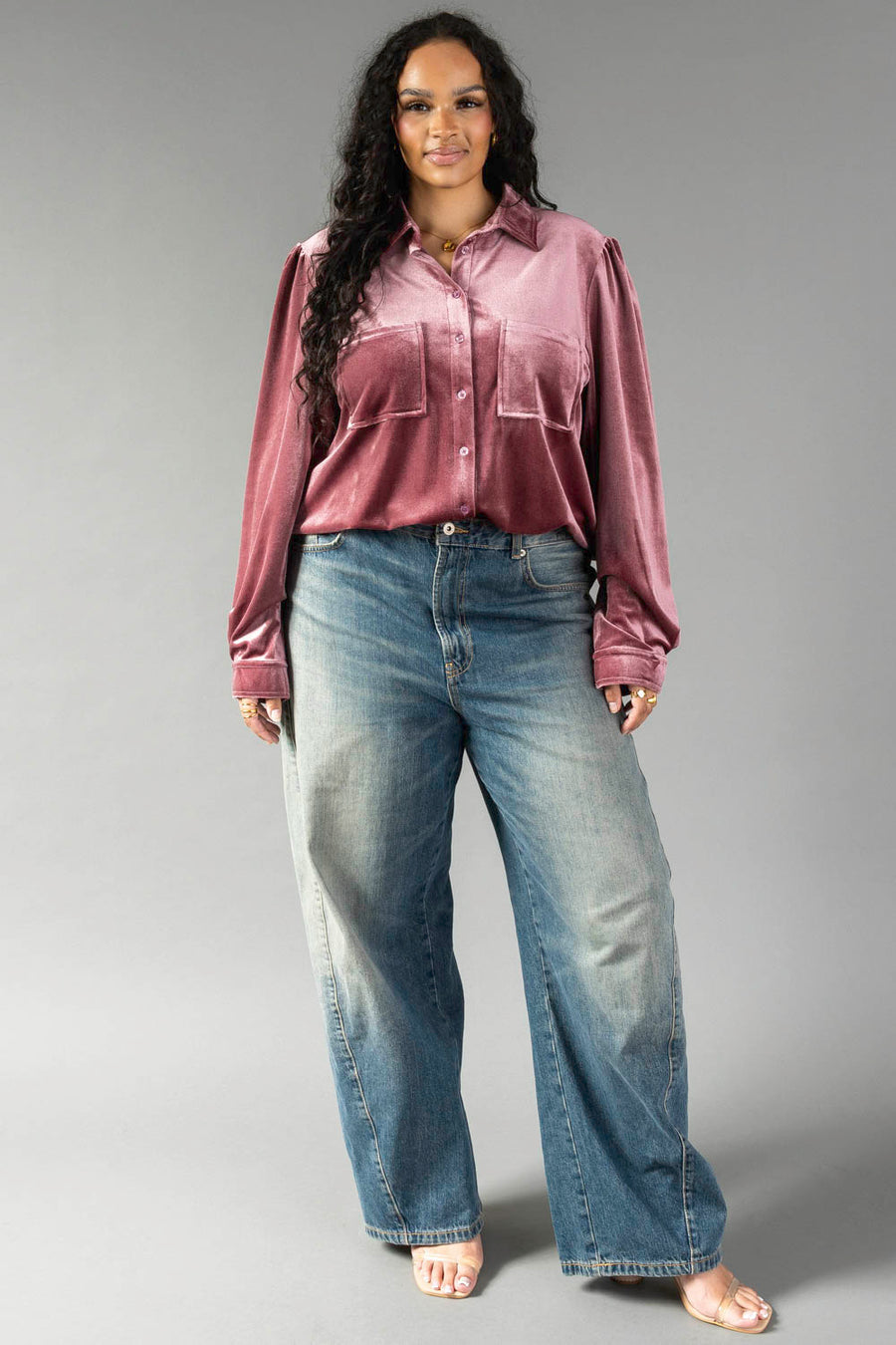 A woman wearing a Mauve Velvet Button Up shirt and wide-leg blue jeans from Panache Apparel Collection.