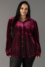 A person wearing a Panache Apparel Collection Maroon Velvet Button Up, a long-sleeved maroon velvet shirt featuring two chest pockets.