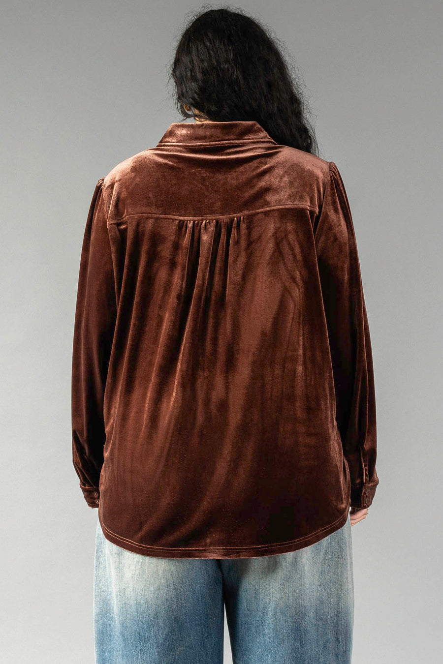 Back view of a person wearing a Brown Velvet Button Up with a pleated back yoke and light-wash jeans.