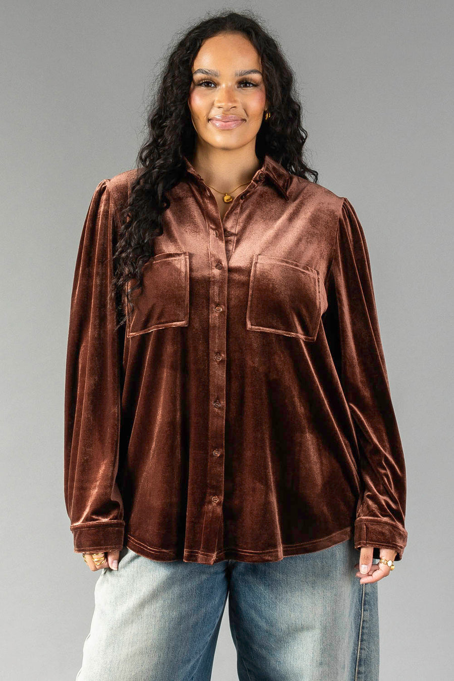 A person wearing a brown velvet Brown Velvet Button Up shirt with two chest pockets and light-wash jeans from Panache Apparel Collection.