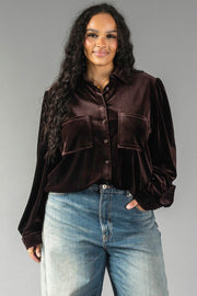A woman wears an Espresso Brown Velvet Button Up in a relaxed fit with long sleeves and two large chest pockets, paired with blue jeans.