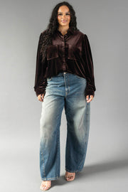 A woman wearing a long-sleeved, espresso brown velvet Espresso Brown Velvet Button Up shirt with two front pockets and wide-leg blue jeans.