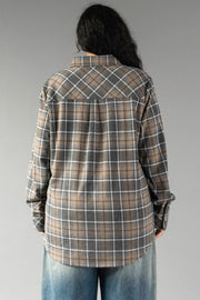 A person with long dark hair, dressed in the Panache Apparel Collection Gray, Tan & White Plaid Button Up and blue jeans, is standing with their back to the camera against a plain gray background.