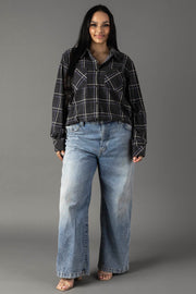 A woman with long dark hair wears the Panache Apparel Collection Dark Gray, Light Blue & White Plaid Button Up and loose, light blue jeans. She stands facing forward, smiling slightly against a plain gray background.