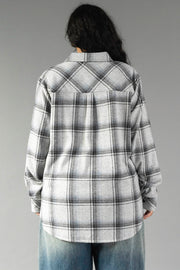 A person with long dark hair is seen from behind, standing against a plain gray background, wearing the Panache Apparel Collection Light Gray, Black & Sage Plaid Button Up along with blue jeans.