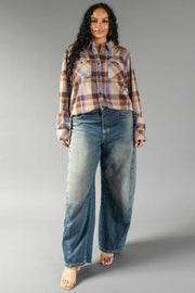 A woman with long curly hair wears the Panache Apparel Collection’s Dark Brown, Blue & Pink Plaid Button Up, paired with loose faded blue jeans and open-toed heels, standing against a plain gray background.