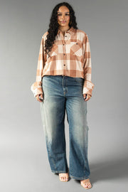 A woman with long dark hair wears the Panache Apparel Collection Cream & Rust Plaid Button Up, faded wide-leg jeans, and sandals, standing against a plain gray background.