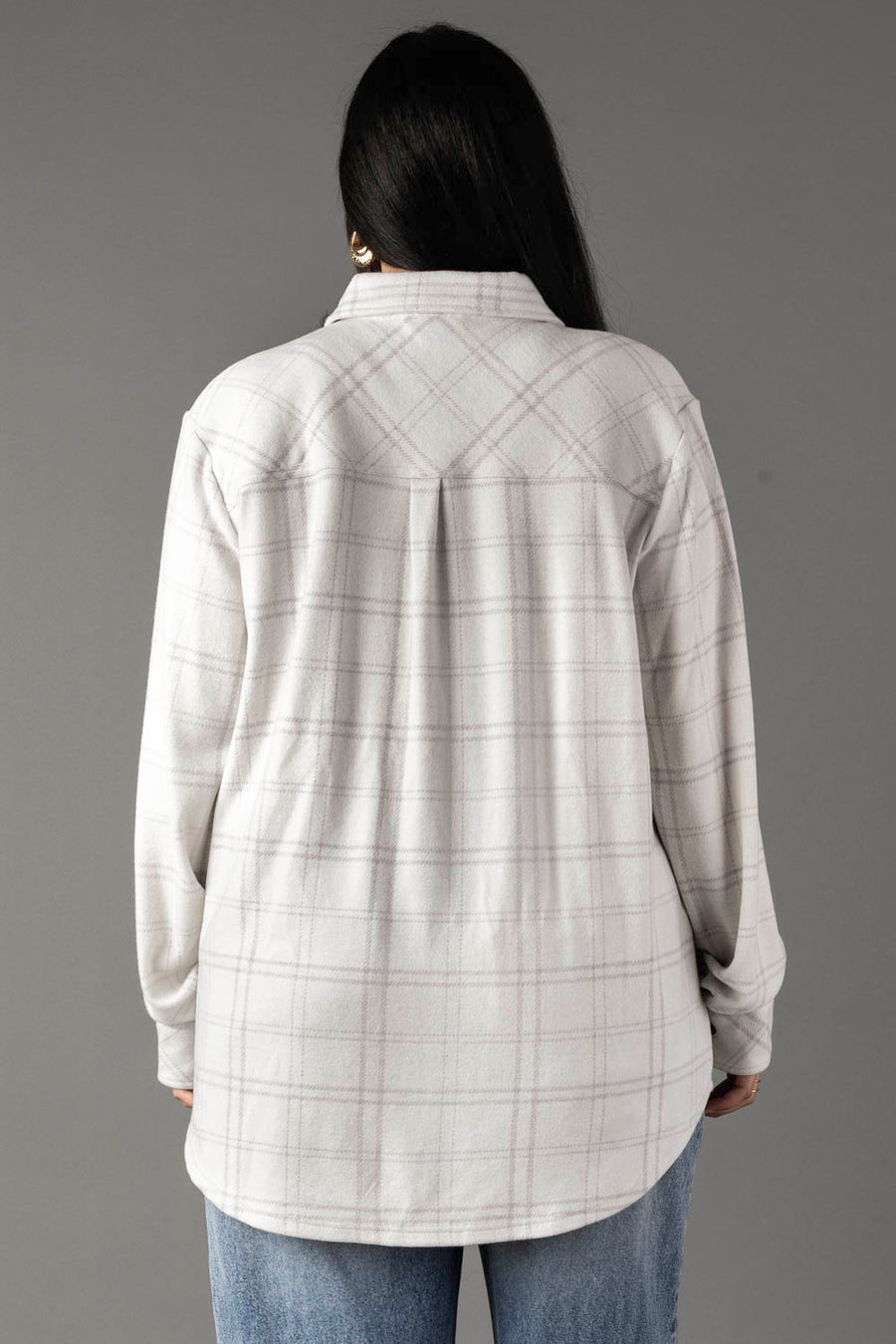 A person with long dark hair is seen from behind, wearing the Panache Apparel Collection White & Light Gray Plaid Button Up and blue jeans against a plain gray background.