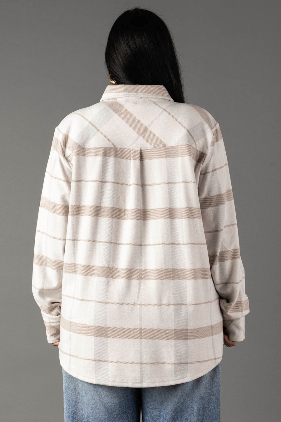 A person with long dark hair, seen from behind, models the Panache Apparel Collection’s Cream, Tan & Gray Plaid Button Up with light blue jeans against a plain gray background.