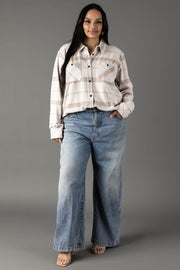A woman stands smiling, wearing the Panache Apparel Collection Cream, Tan & Gray Plaid Button Up paired with loose-fitting blue jeans. She has long dark hair and her hand in her pocket, posing against a plain gray background.