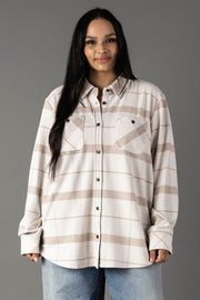 A woman with long dark hair wears the Panache Apparel Collection Cream, Tan & Gray Plaid Button Up featuring two chest pockets, paired with light blue jeans, as she stands against a gray background.