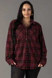A woman wearing the Panache Apparel Collection Maroon & Black Plaid Button Up stands against a gray background, looking at the camera and smiling softly.