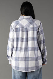 A person with long dark hair, wearing the Panache Apparel Collection’s White & Dusty Blue Plaid Button Up and light blue jeans, is standing with their back to the camera against a plain gray background.