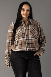 A woman with long dark hair wears the Panache Apparel Collection Tan, White & Black Plaid Button Up and black jeans, standing against a plain gray background with one hand in her pocket, smiling slightly.