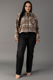 A woman stands facing forward, wearing the Panache Apparel Collection’s Tan, White & Black Plaid Button Up with black jeans and clear-heeled shoes. The background is plain gray.