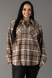 A woman with long dark hair smiles while wearing the Panache Apparel Collection Tan, White & Black Plaid Button Up and black pants, standing against a plain gray background.