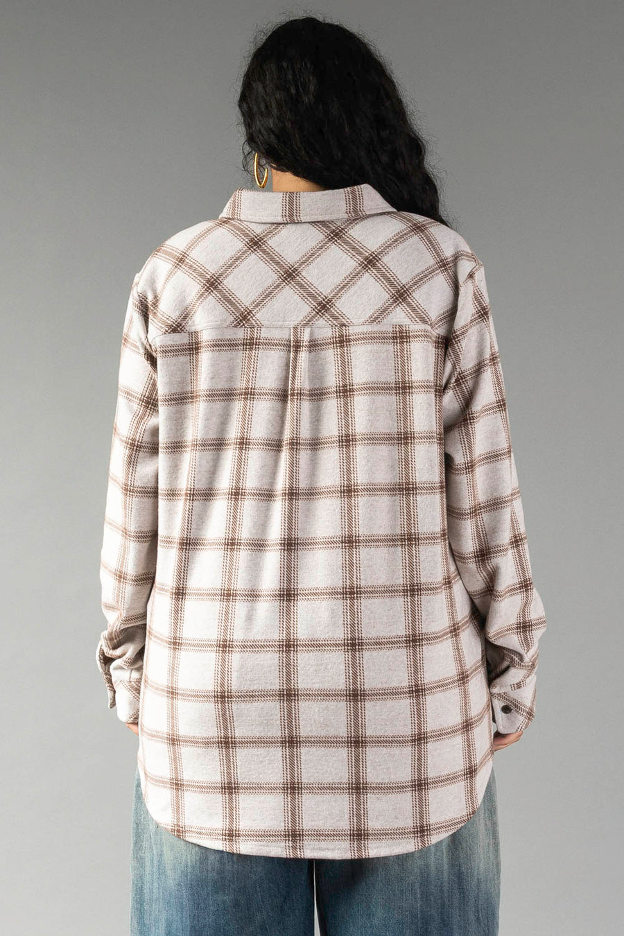 A person with long dark hair, seen from behind against a plain gray background, is wearing the Panache Apparel Collection Light Taupe & Brown Plaid Button Up paired with blue jeans.