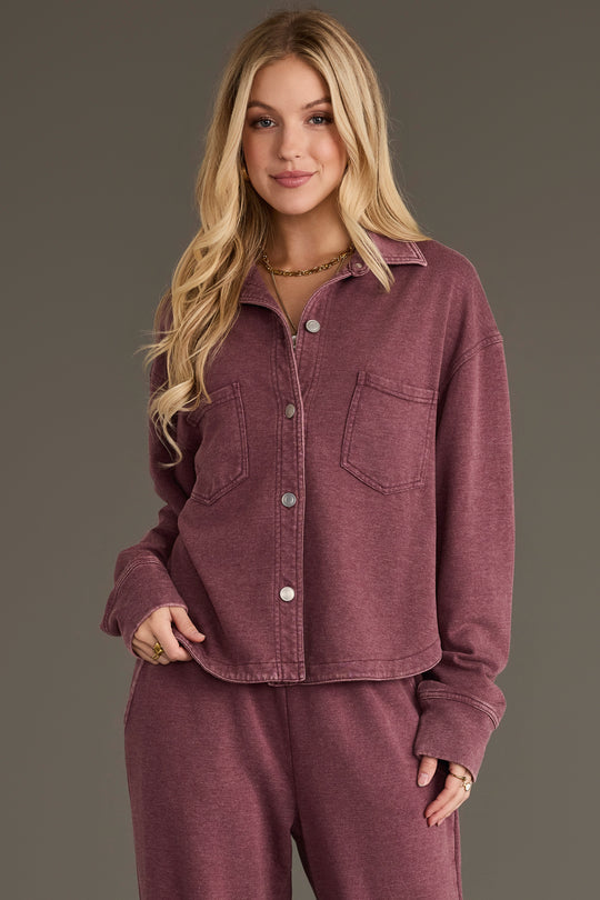 A woman with long blonde hair wears the Merlot Cropped Washed Soft Button Up from Panache Apparel Collection, featuring two chest pockets and paired with matching pants, standing against a plain background.